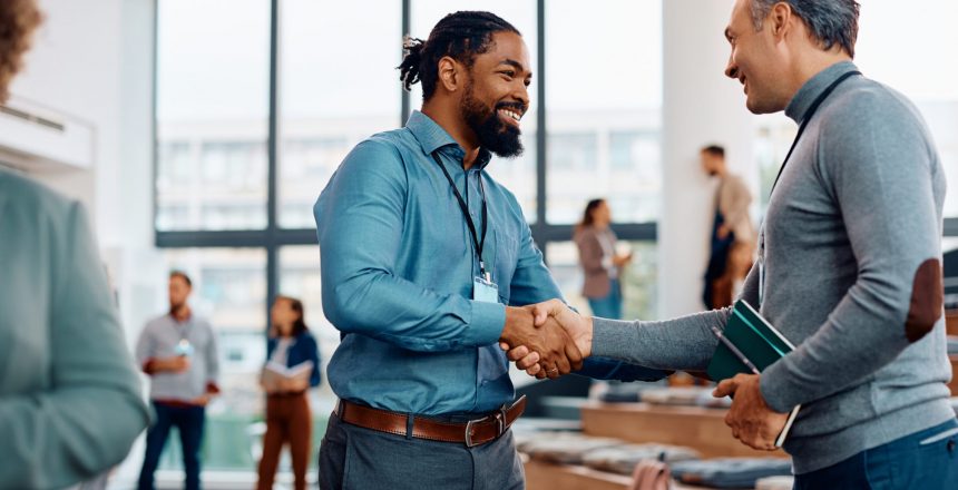 happy businessmen greeting while attending an education event at conference hall e1694673006317
