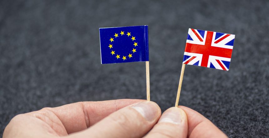 man holding small paper flags eu great britain as symbol brexit concept picture scaled